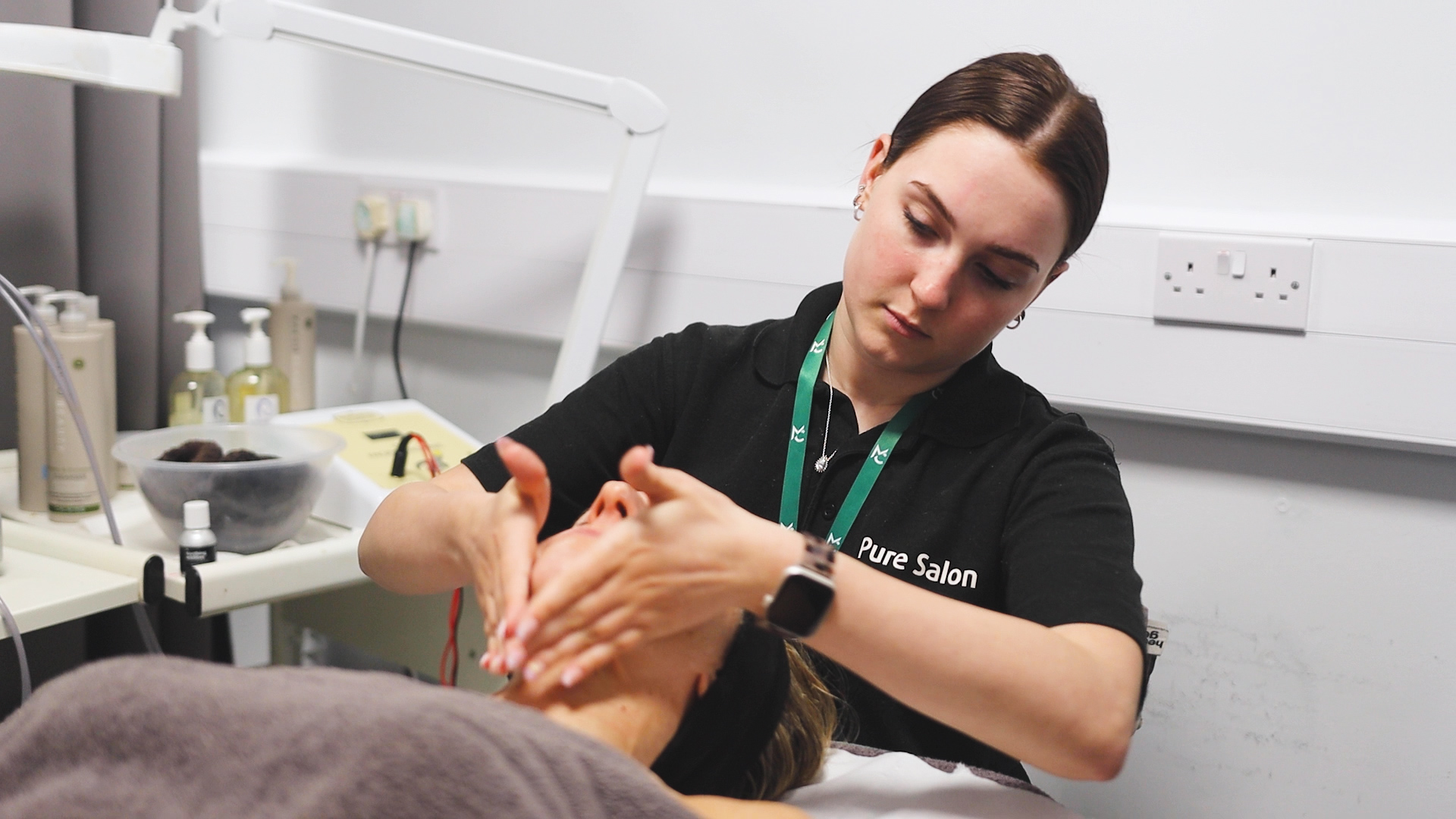 a beauty student doing a facial massage treatment on a client