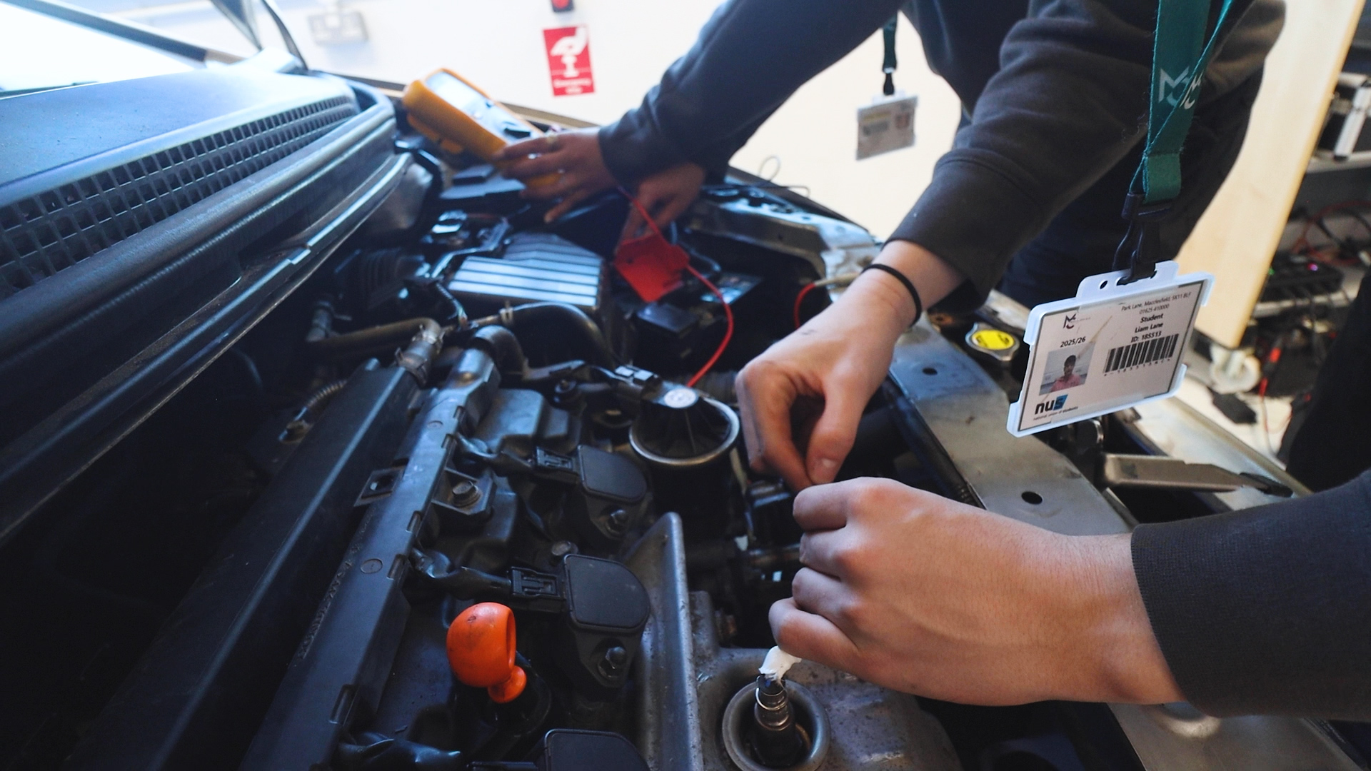 hands are working on a car engine