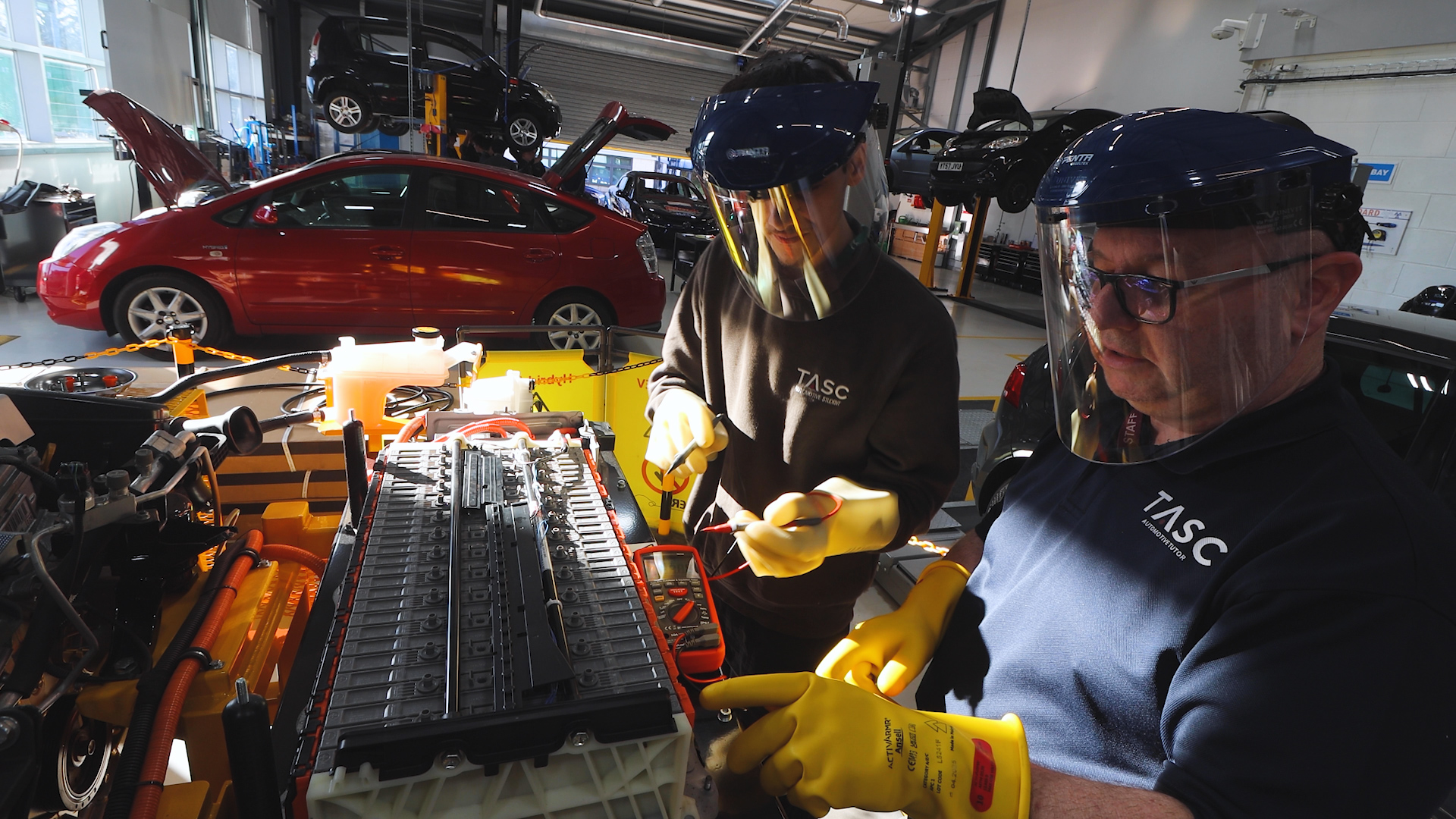 an automotive student and teacher working on an electrical vehicle