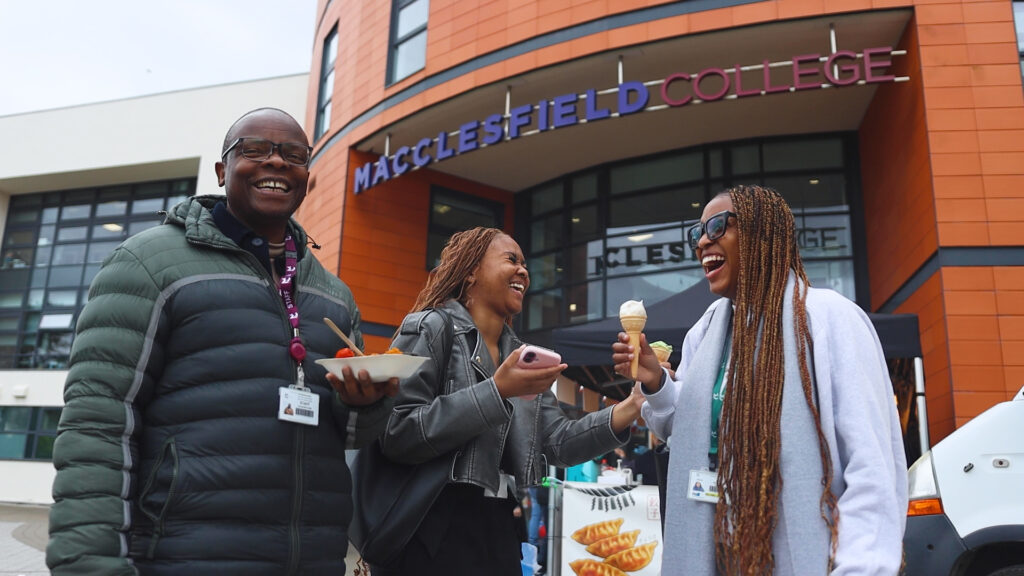 three people are smiling outside of macclesfield college holding food