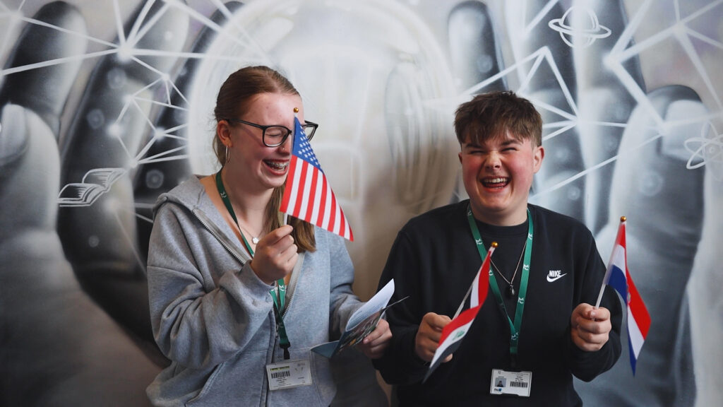 two students holding flags whilst smiling