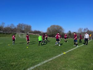 a group of students wearing football kits are playing football