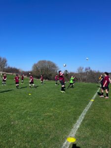 a group of students wearing football kits are playing on a football pitch
