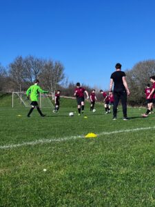 a group of students wearing football kits are playing on a football pitch