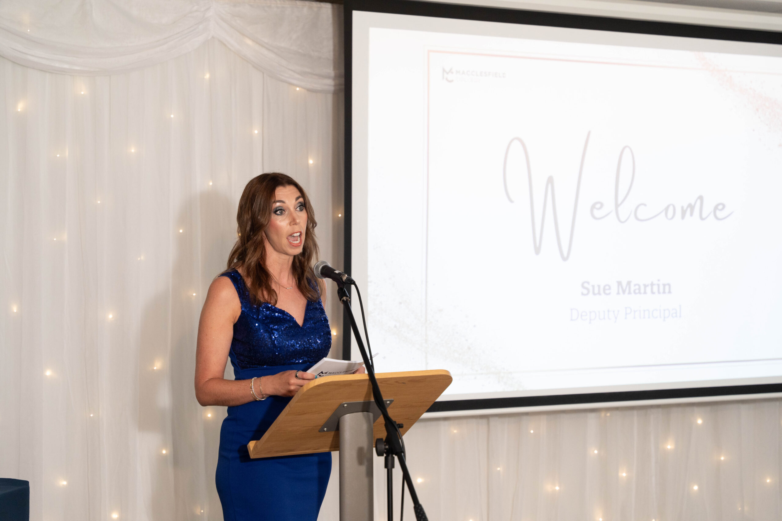 a woman is standing behind a lectern presenting during an award ceremony