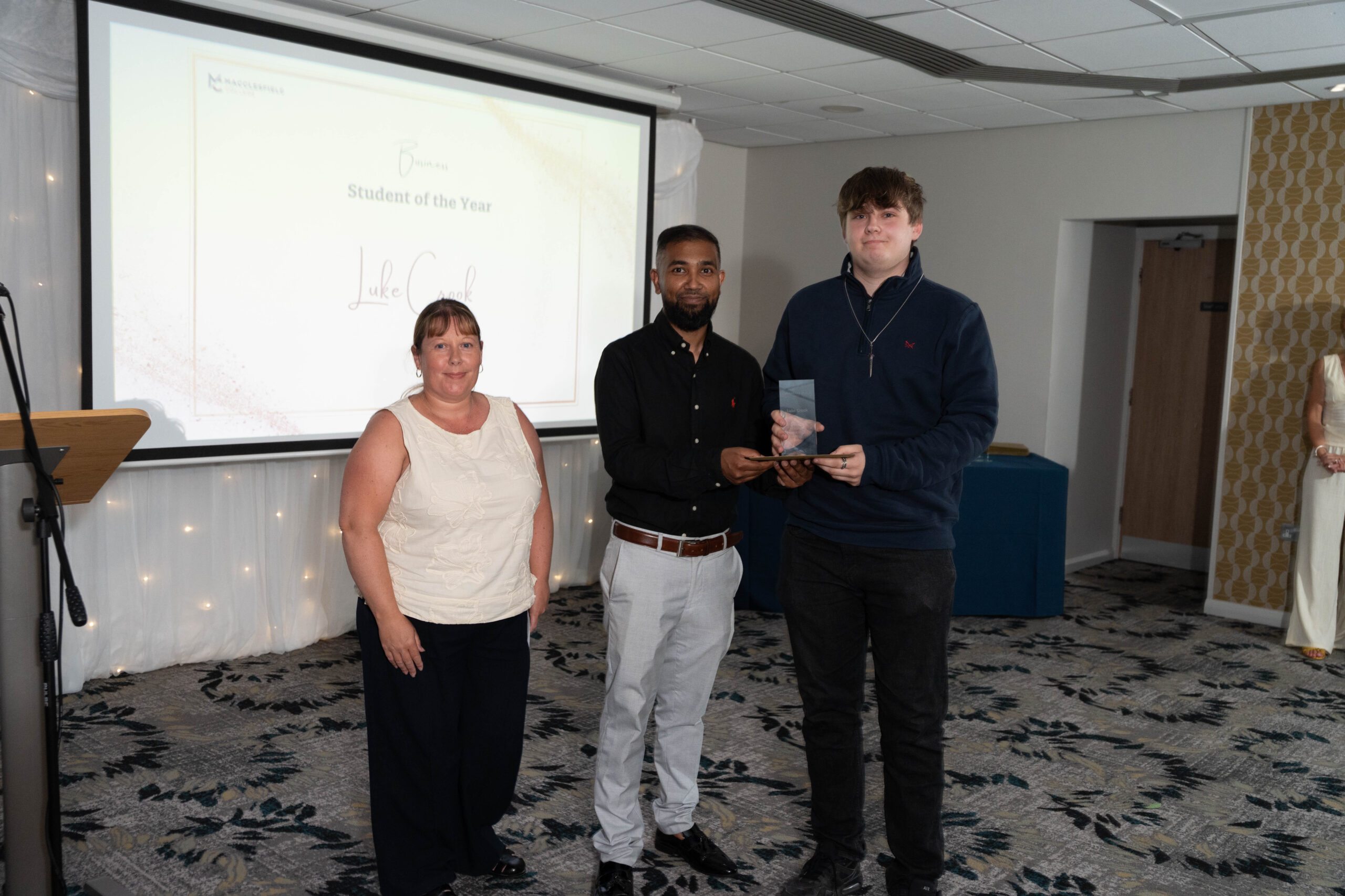 Two staff members and a student are smiling for a photo together during an awards ceremony