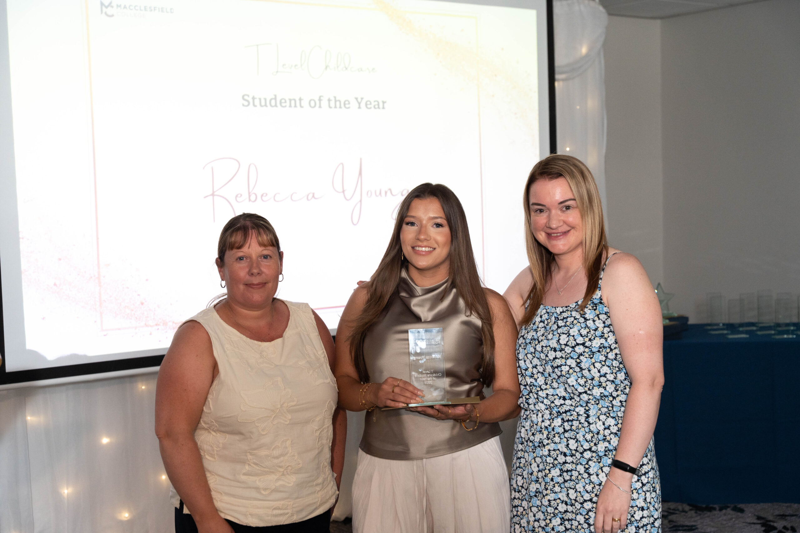 Two female staff members and a female student are smiling for a photo together during an student awards event