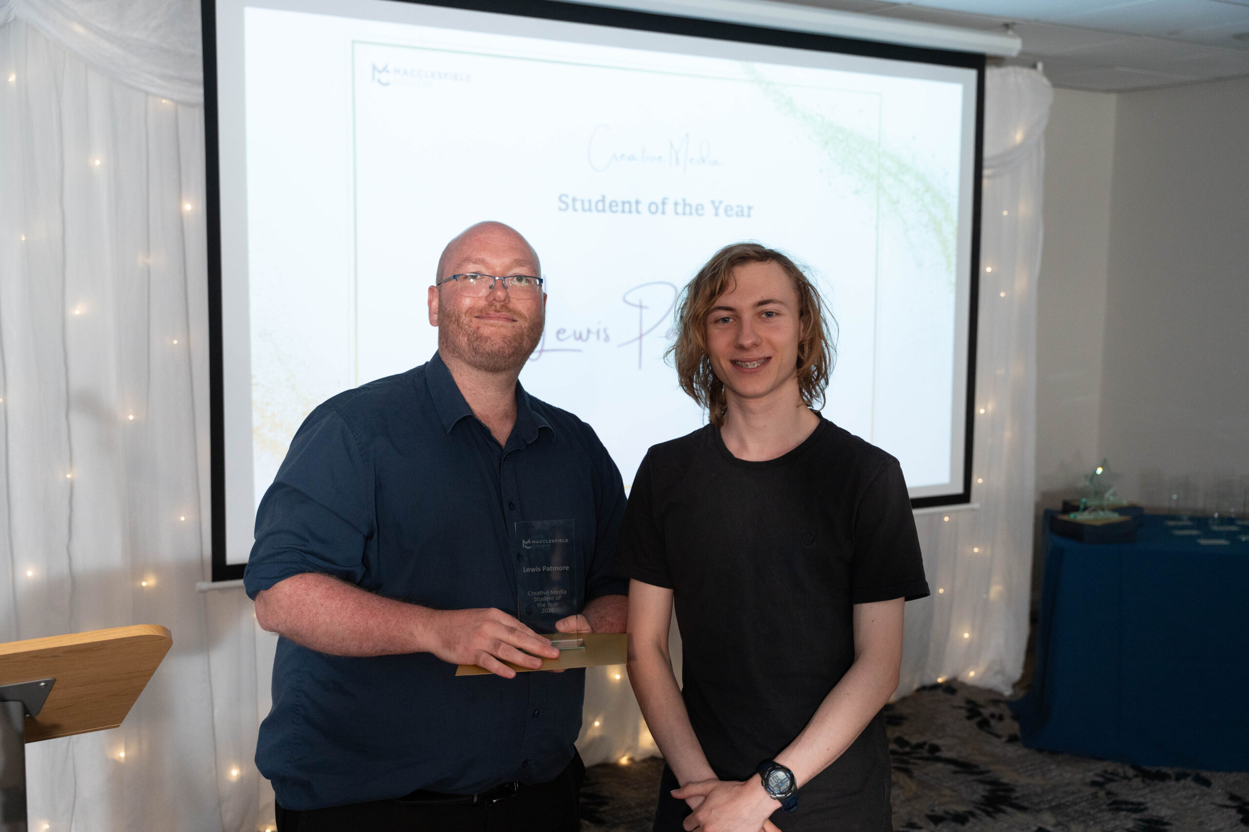 a male staff member and male student are posing for a photo during a student awards event