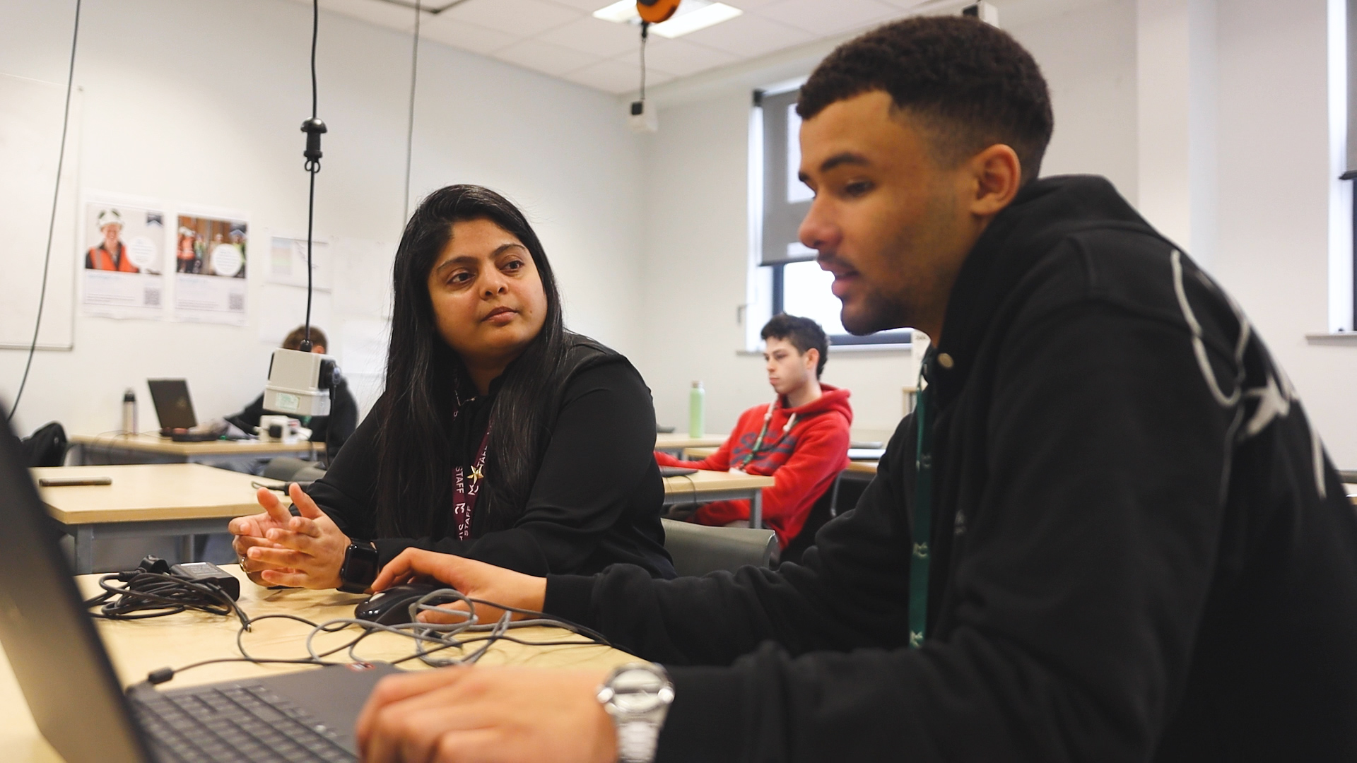 a teacher and a student are working on a laptop together