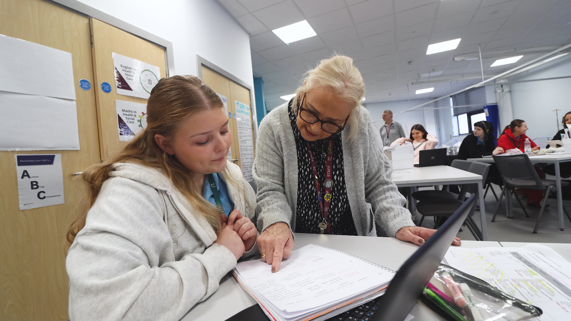 a health student and a teacher look at notebook together
