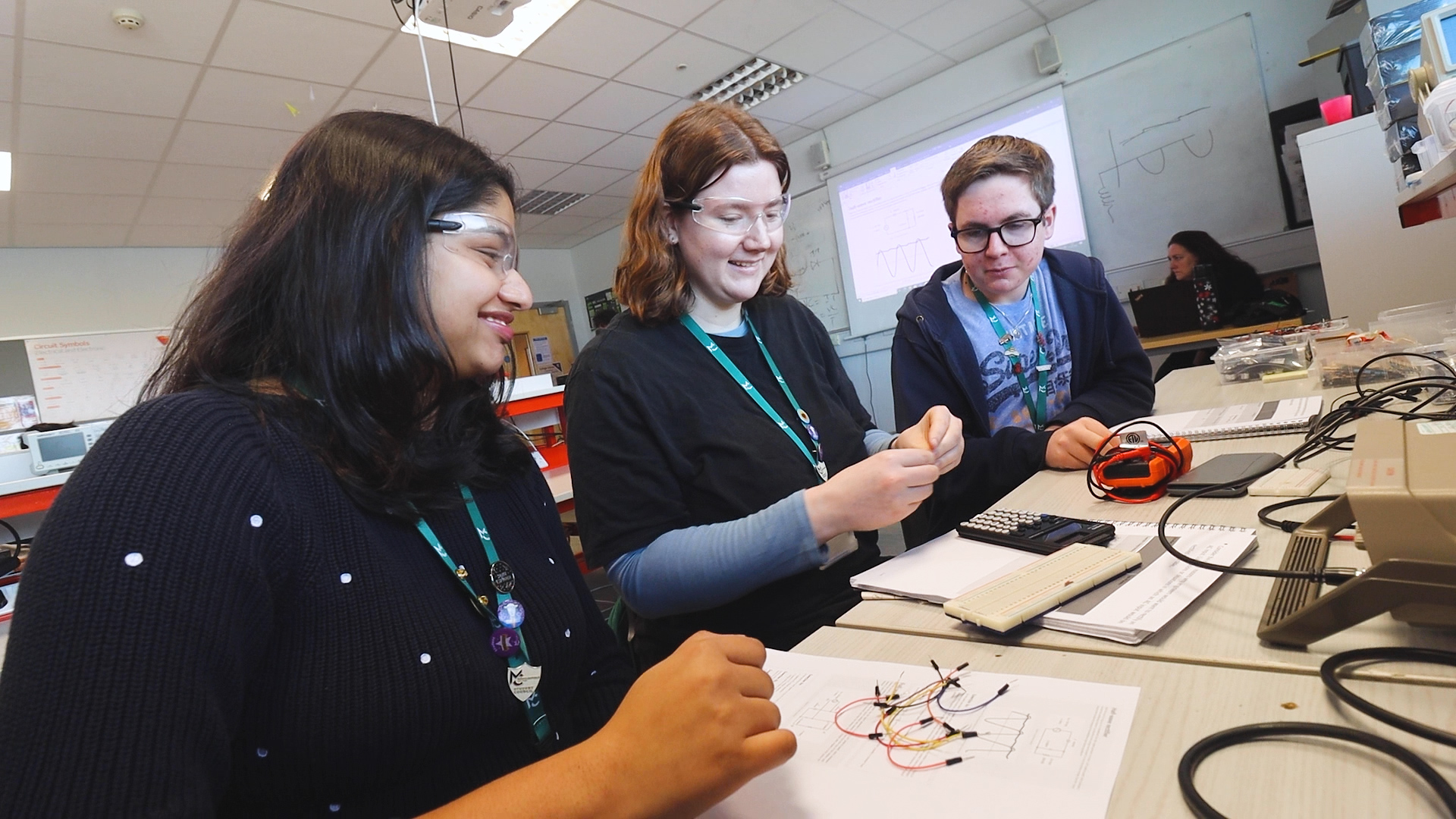 three engineering students are working together in an engineering classroom