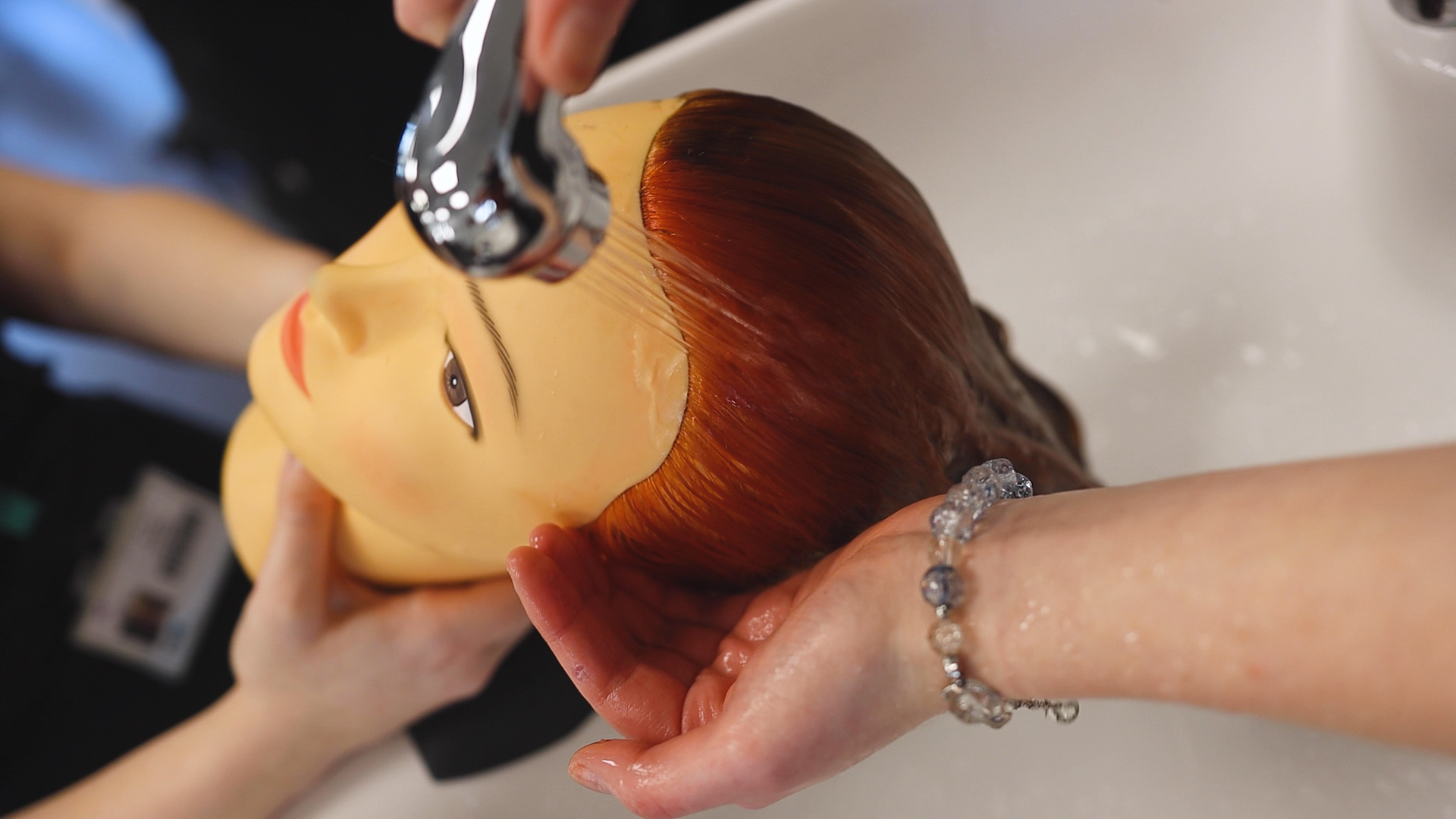 hairdressing students practice washing hair techniques on a mannequin head