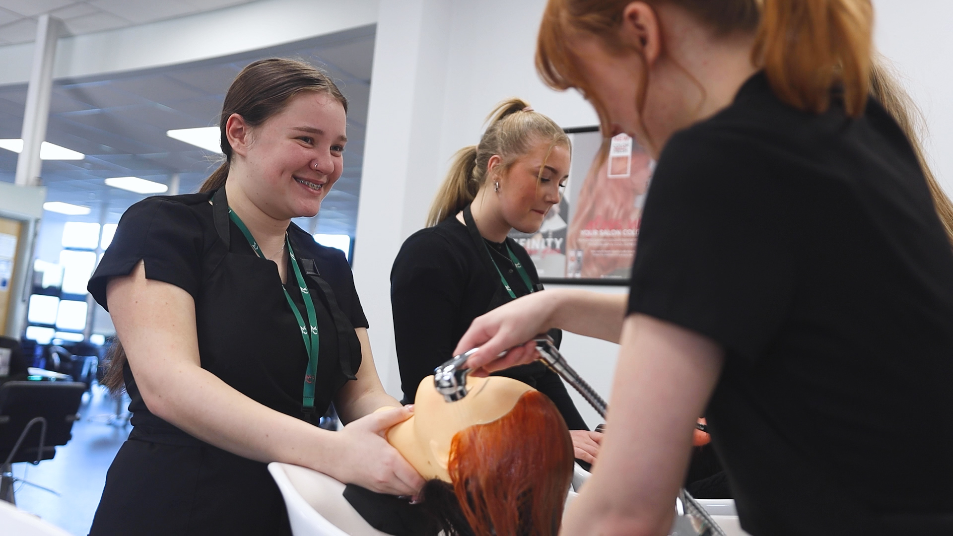 hairdressing students practice washing hair techniques on a mannequin head