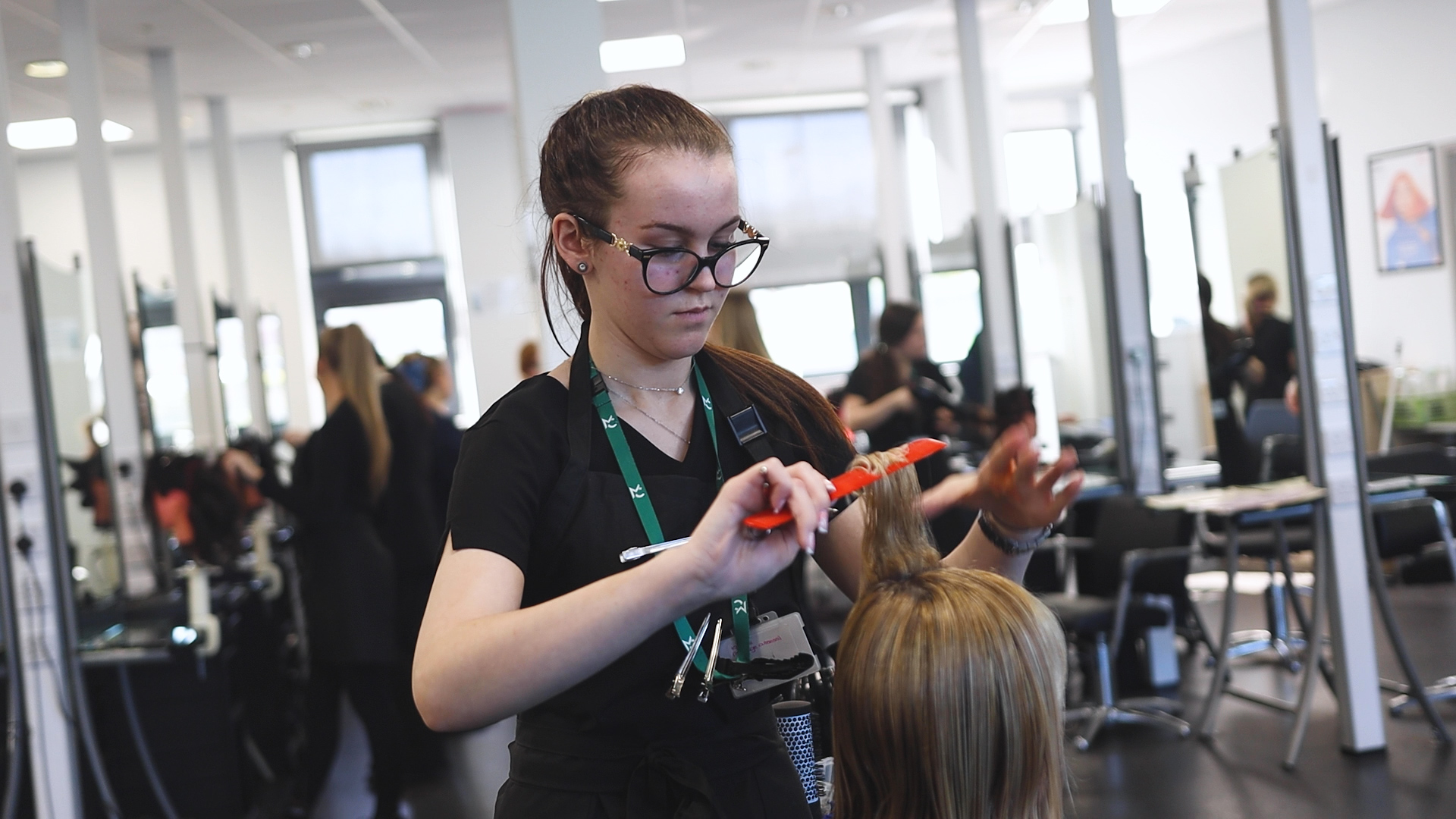 a hairdressing student practices styling techniques on a mannequin head