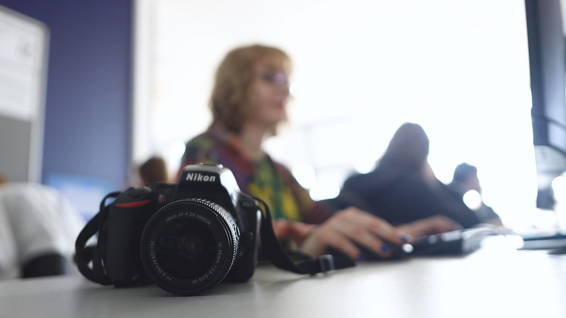 A Creative Media student is working on a computer with a camera next to them