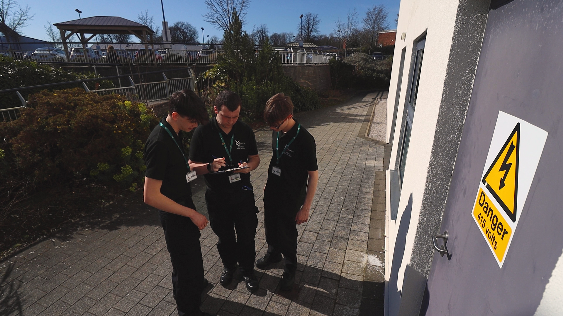 Three public service students are standing outside of Macclesfield College looking at a clipboard