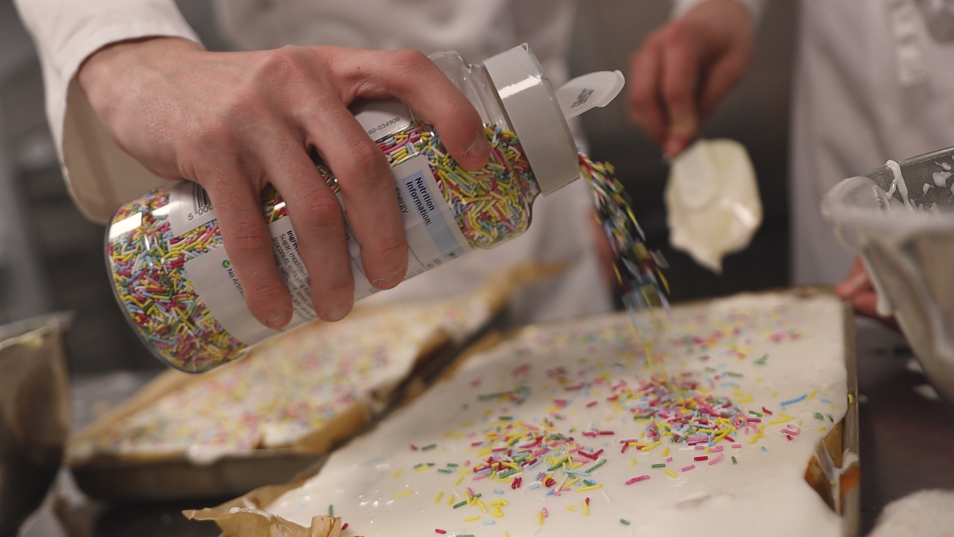 a student is putting sprinkles on a cake