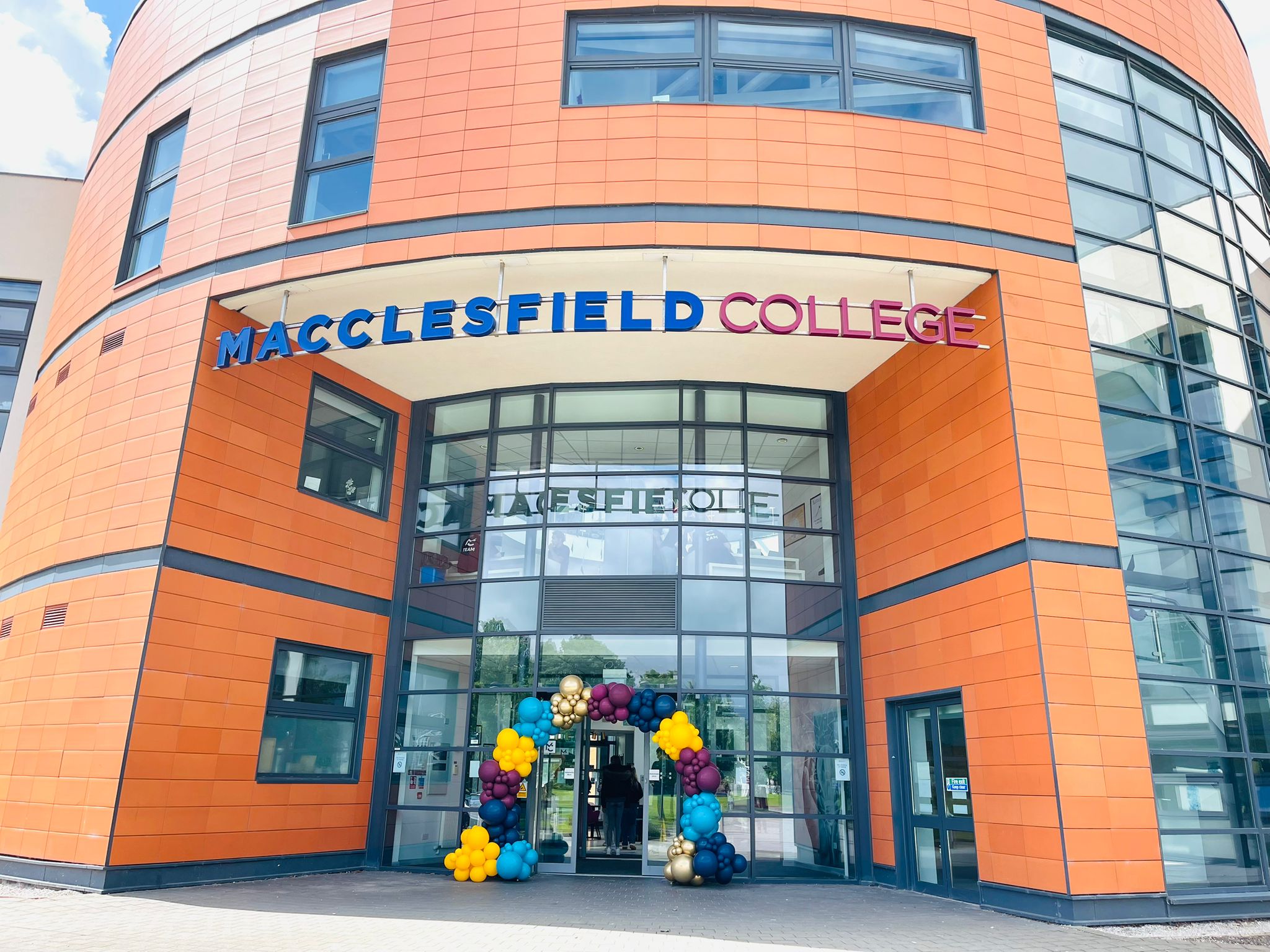 A colourful balloon arch is placed outside of macclesfield college
