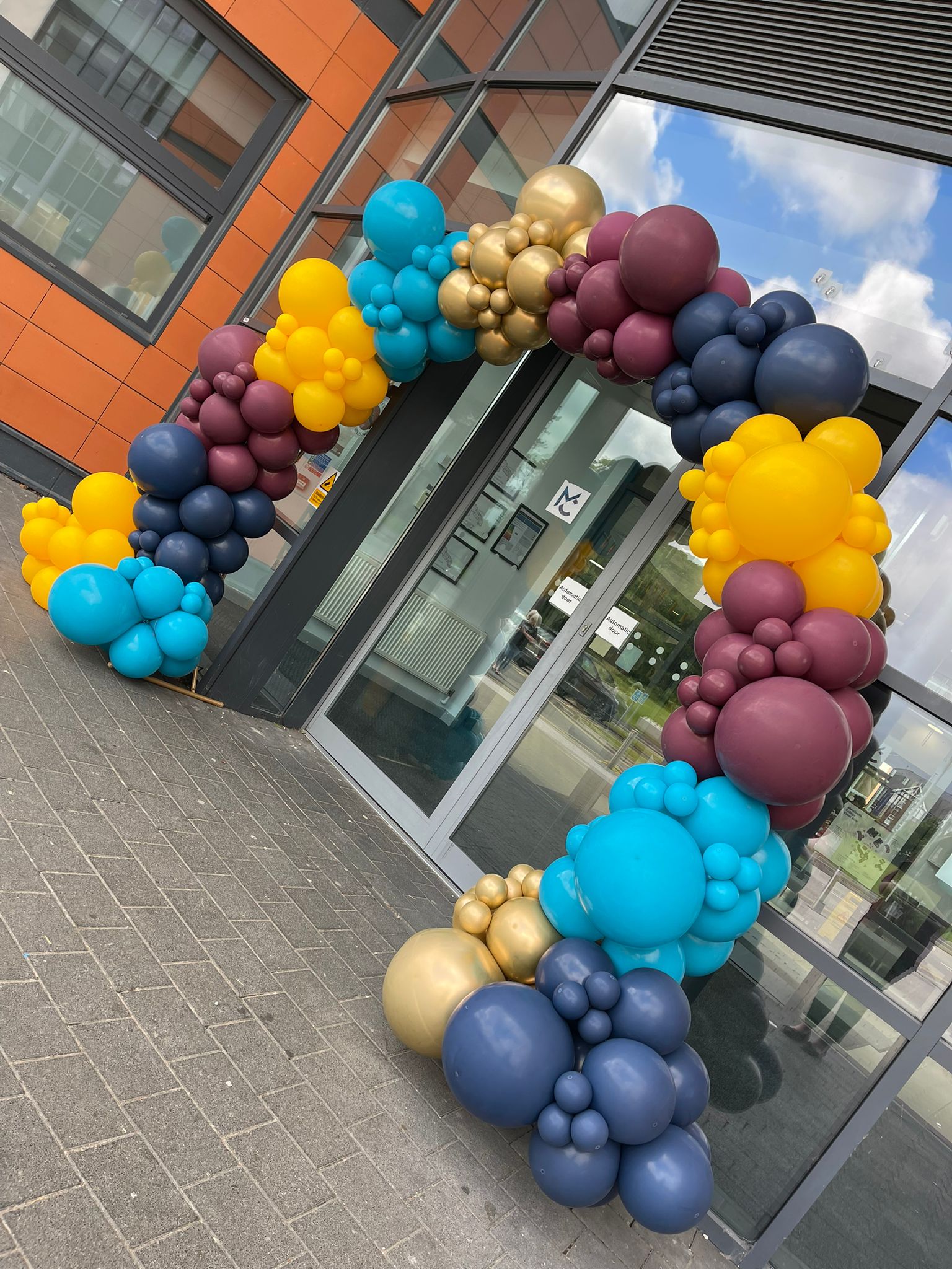 a colourful balloon arch is outside macclesfield college