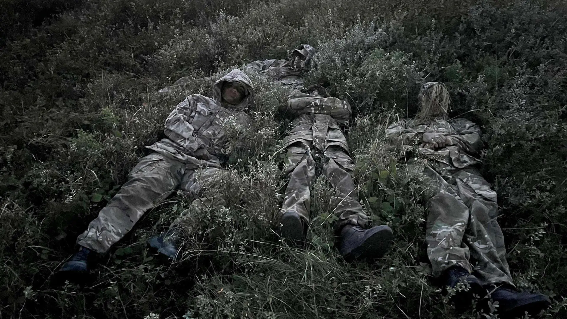 A group of public service students wearing army uniforms are practicing camouflage techniques