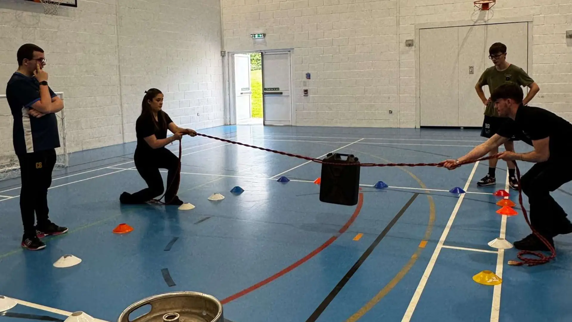 A group of public service students are taking part in an activity where they are lifting a barrel with a rope