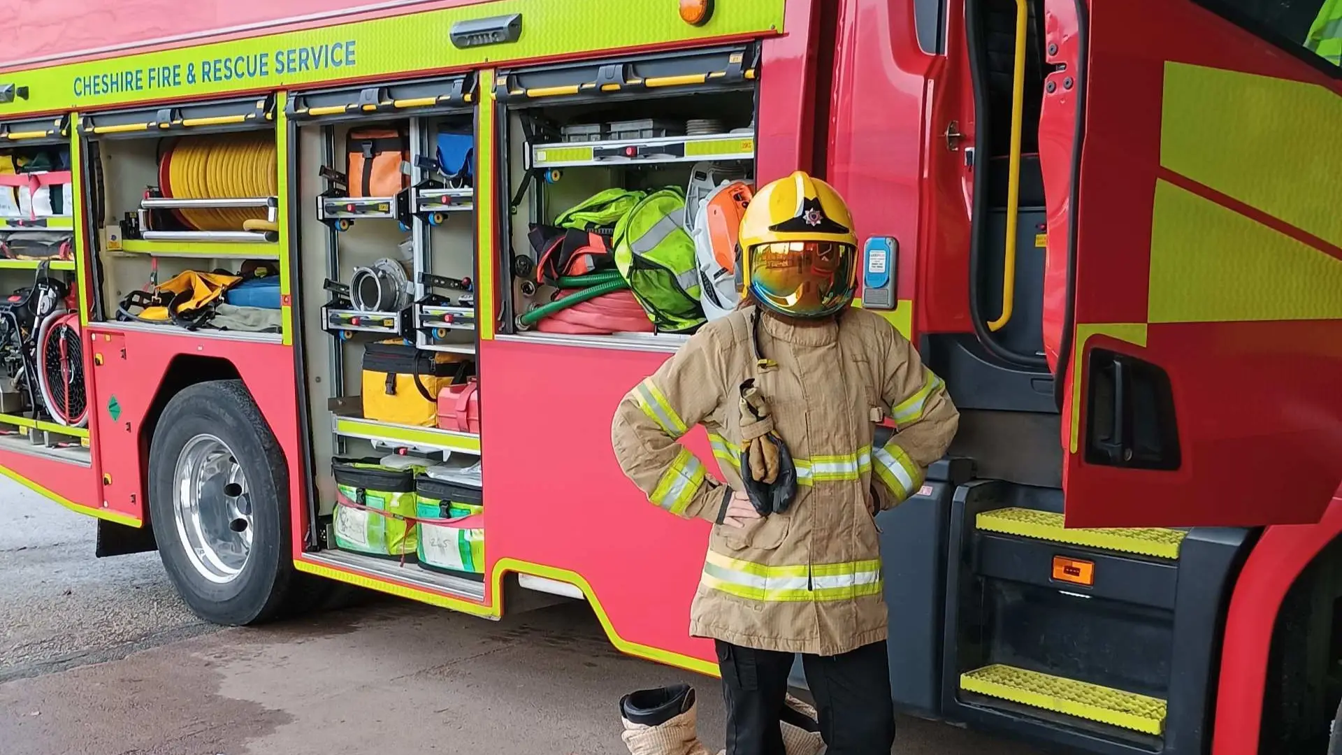 A public service student dressed in a fire worker uniform is standing by a fire truck