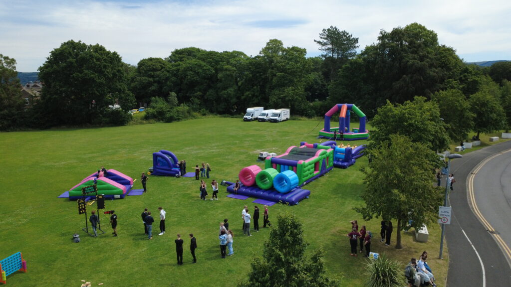 On a field there is a group of students and inflatable game activities