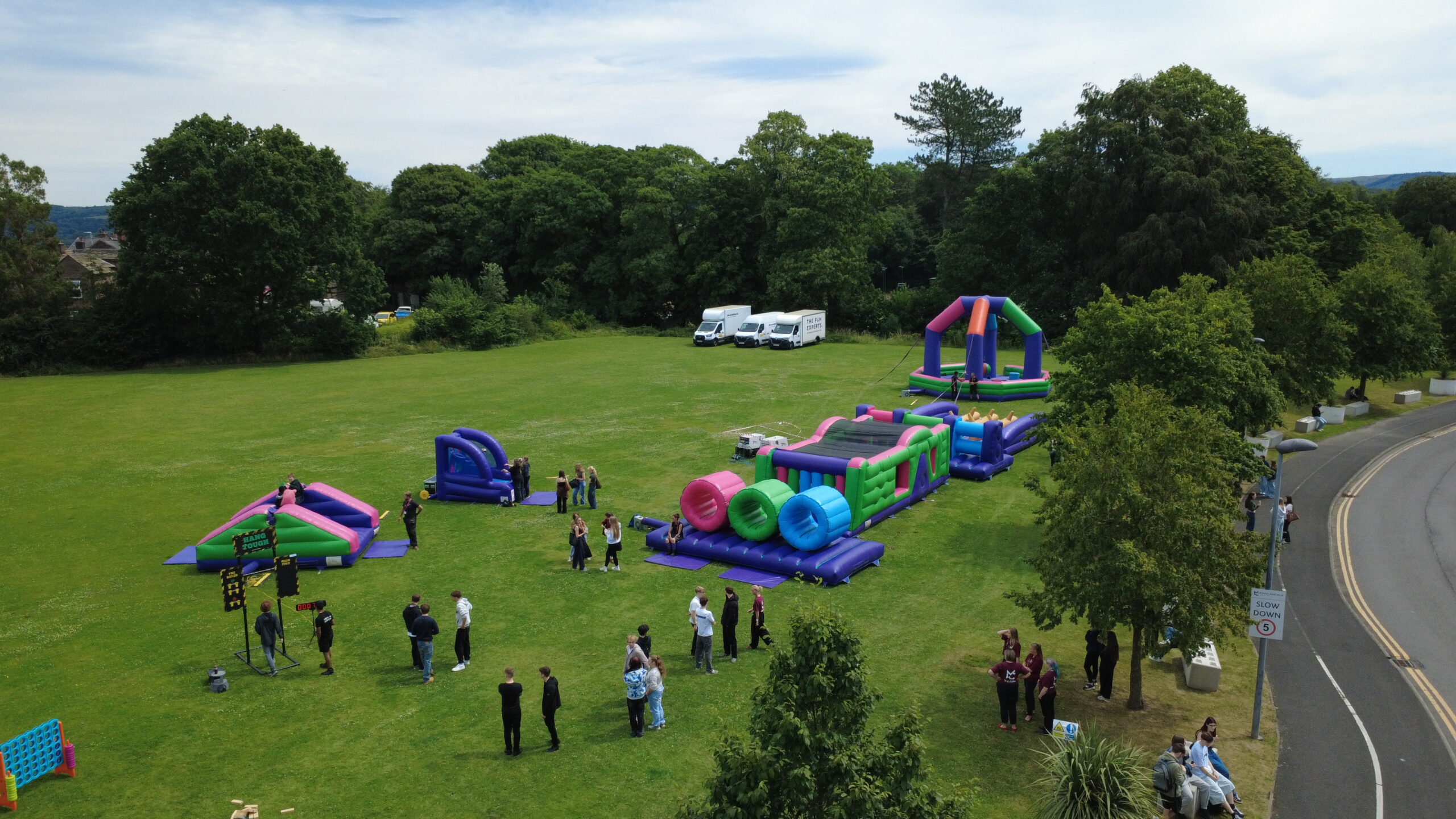 On a field there is a group of students and inflatable game activities
