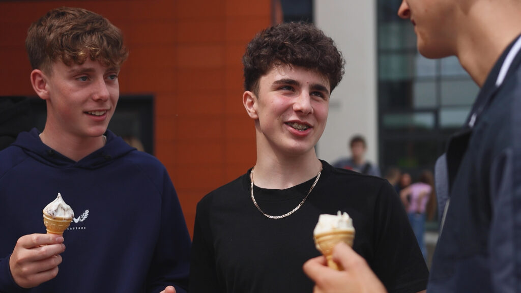 two male students are smiling while holding ice creams