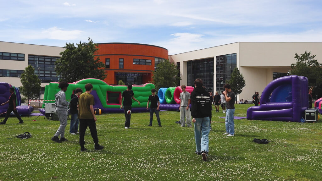 A group of students are playing football on a field at Macclesfield College