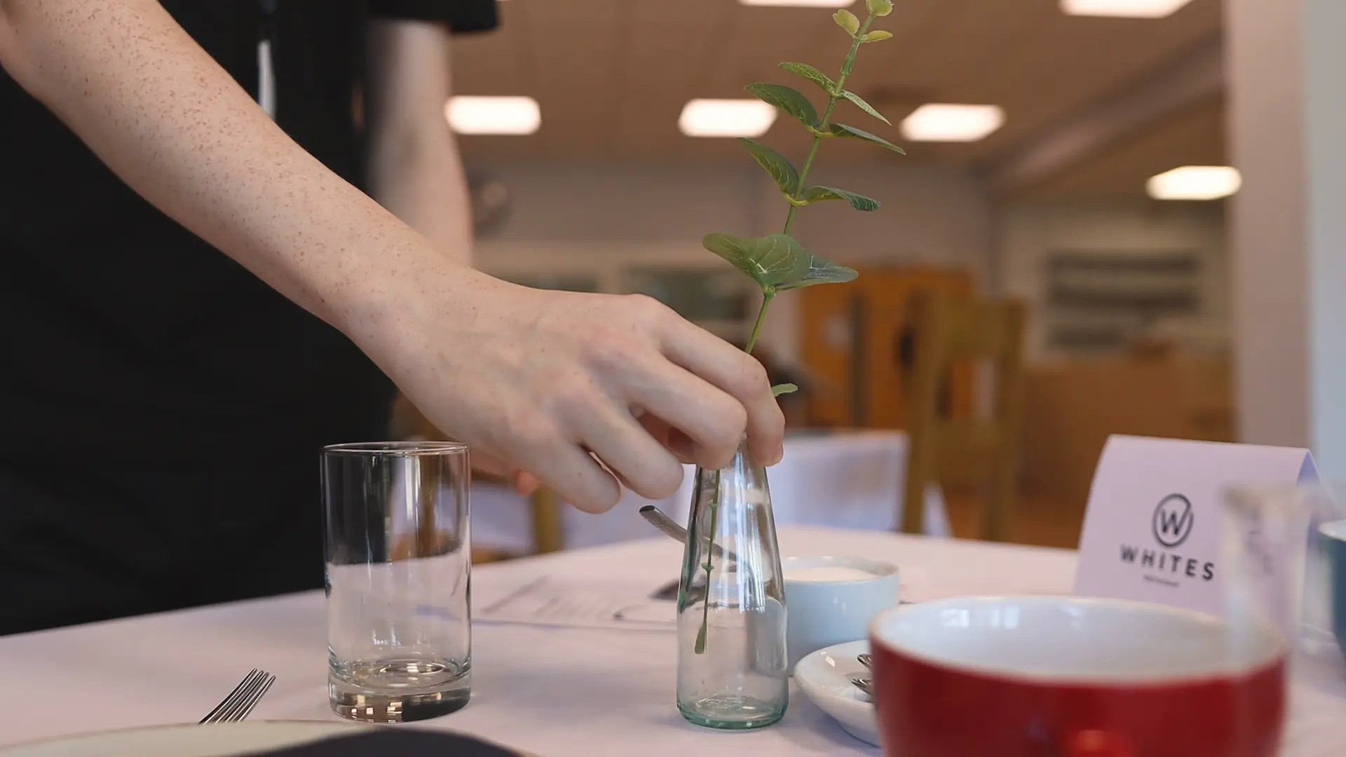 A whites chef academy student is setting up a table for a dinning event