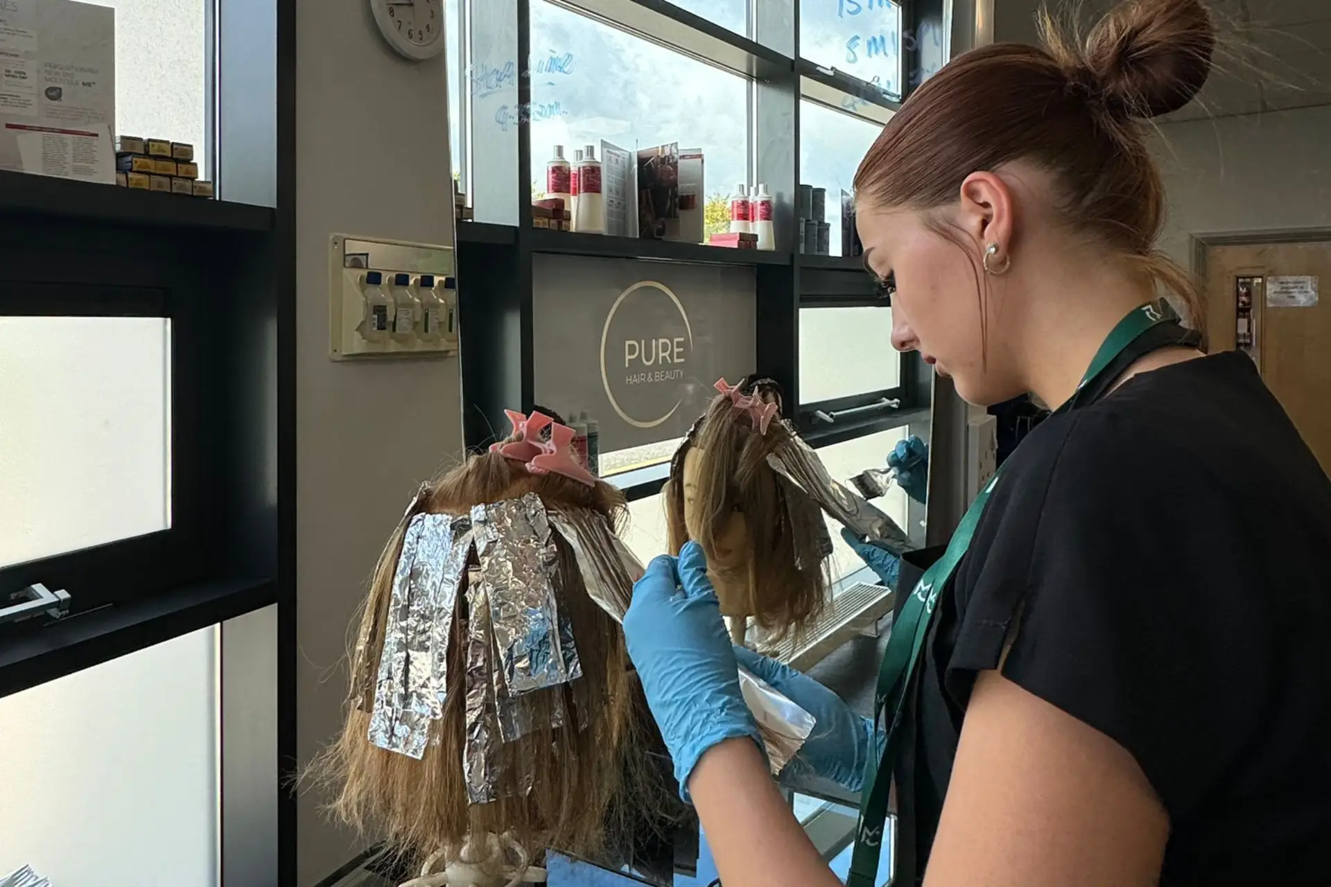 A hairdressing student is practising colour techniques on a mannequin head.