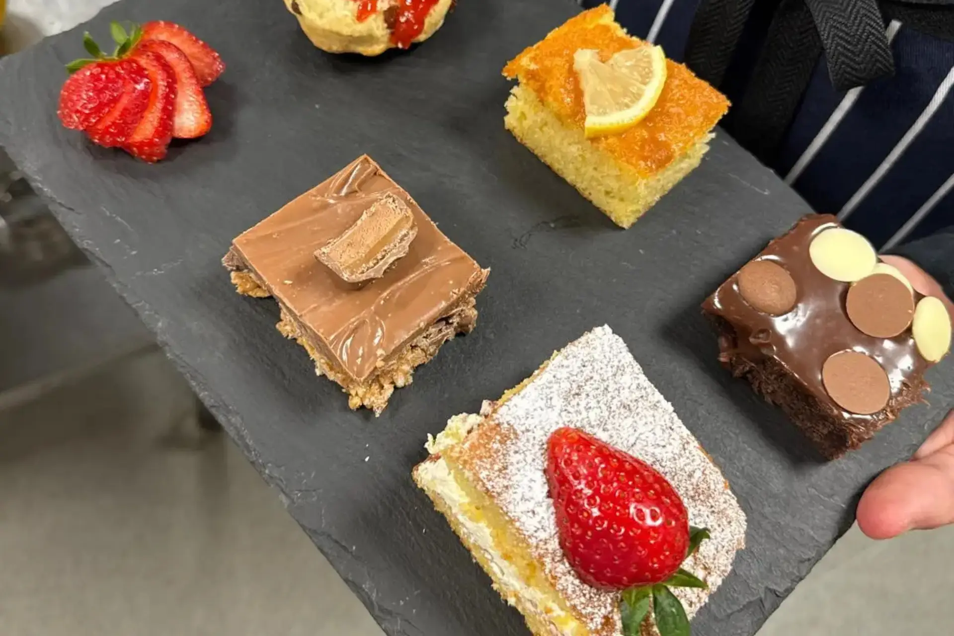 A selection of cakes is neatly presented on a black tray