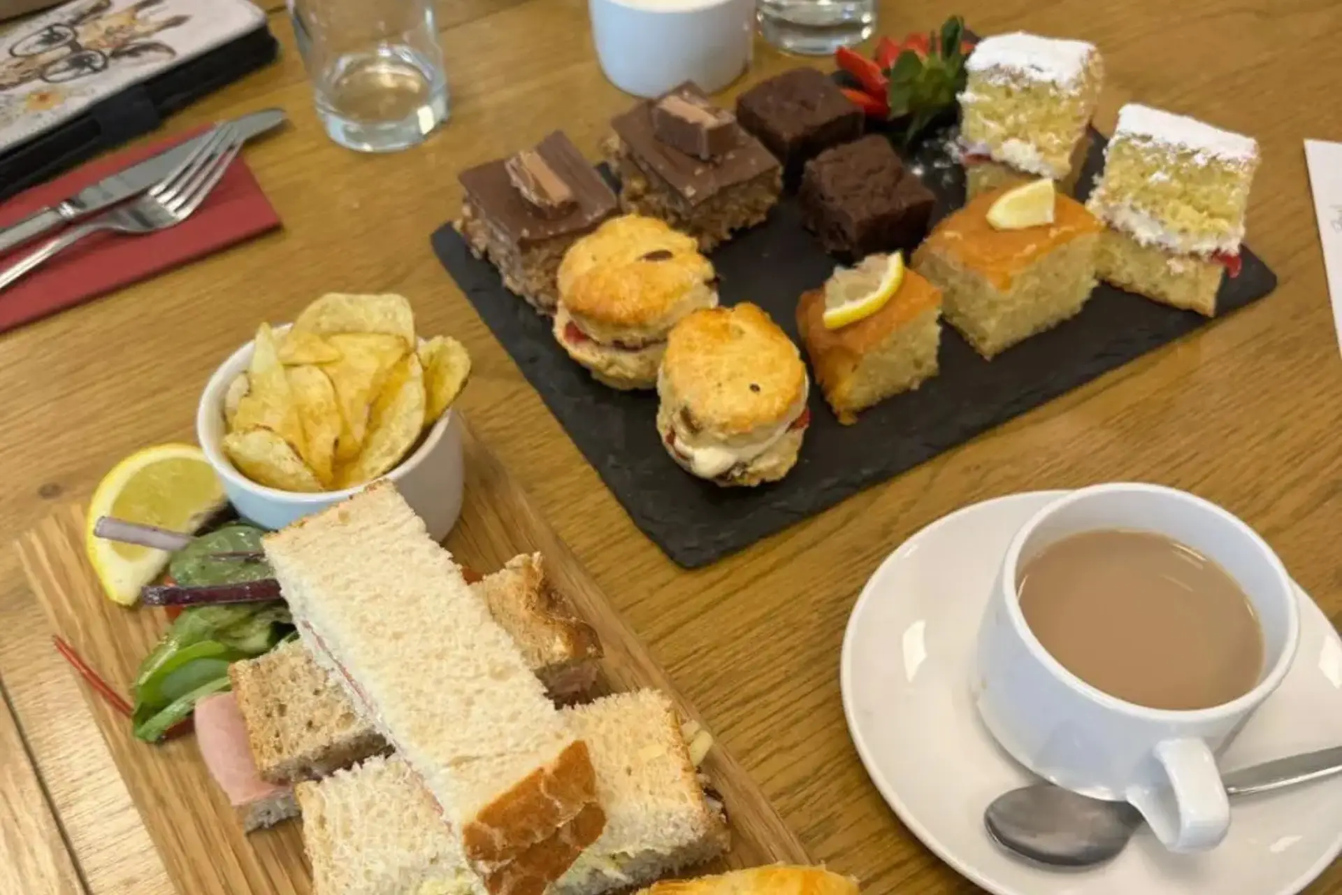 A collection of cakes and sandwiches is neatly placed on a table.