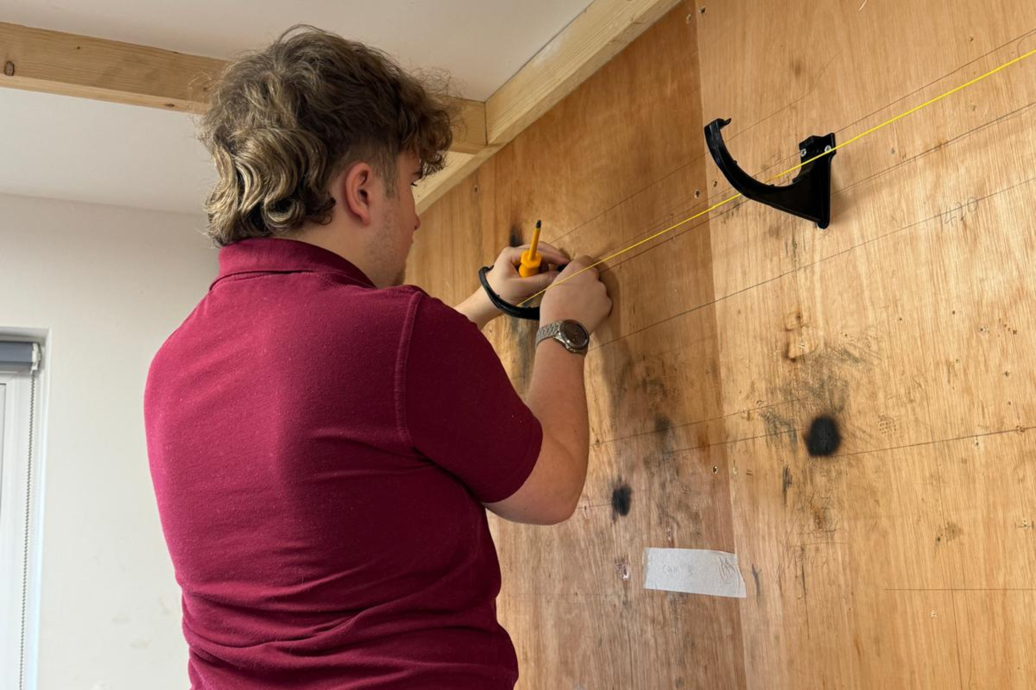 A plumbing student is measuring pipework