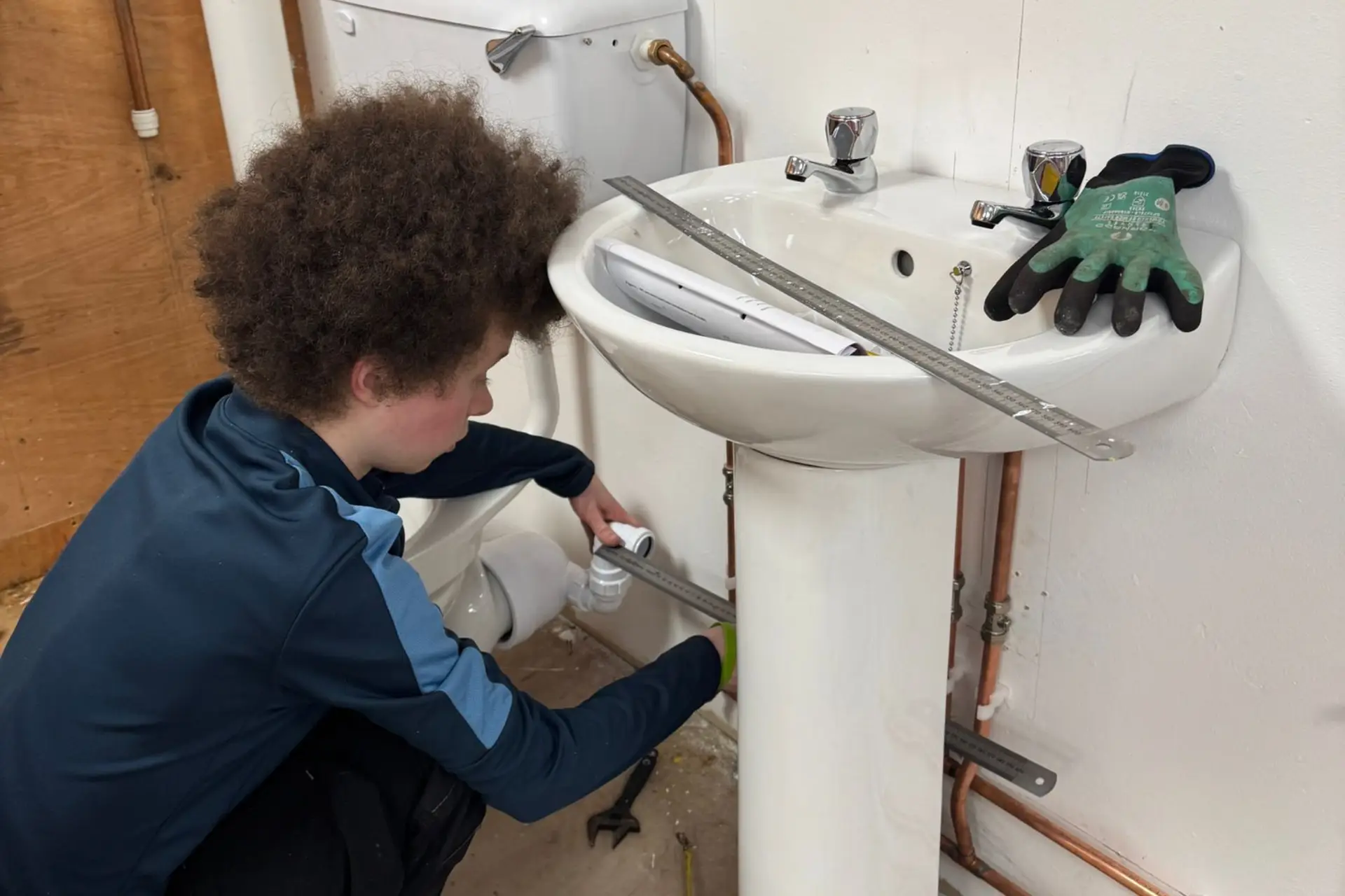 A plumbing student is working on a sink