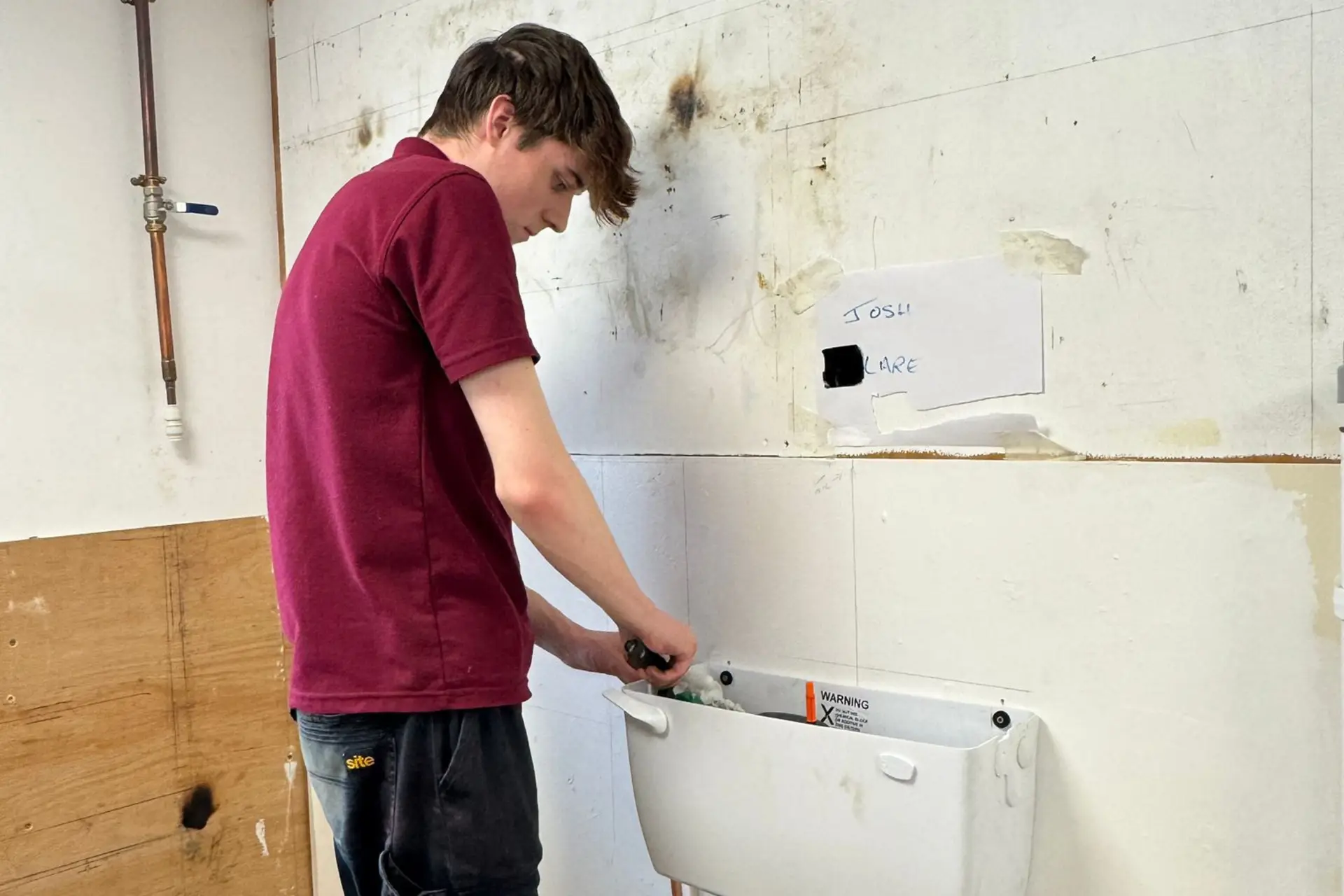 A plumbing student is working on a toilet
