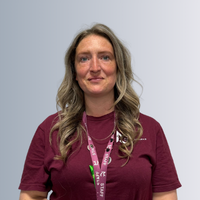 A headshot of a female staff smiling, behind them is a grey background