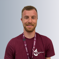 A headshot of a male staff smiling, behind them is a grey background