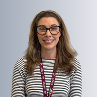A headshot of a female staff smiling, behind them is a grey background