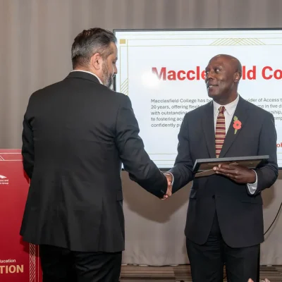Two people are shaking hands on a stage with one person accepting an award.