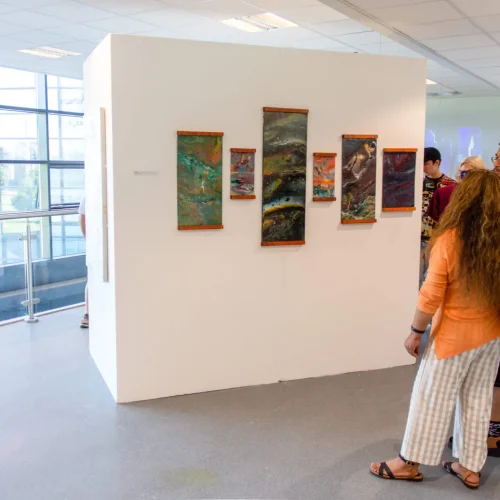 People looking at artwork created by Art students during Macclesfield College's Art and Media End of Year Show