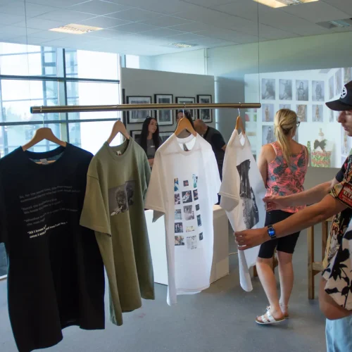 A group of people viewing T-shirts designed by Art students during Macclesfield College's End of Year Art and Media Show.