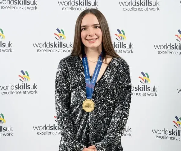A student wearing a gold medal is smiling for a photo